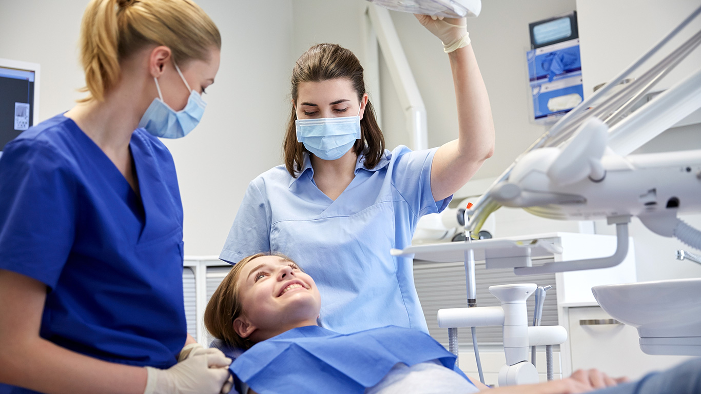 Female Dentist and hygienist working with patient